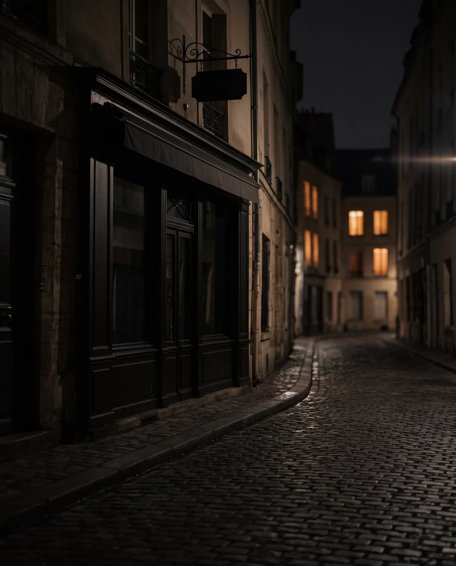 Fațada întunecată a unui local noaptea, în timp ce ferestrele de mai departe de pe stradă sunt luminate