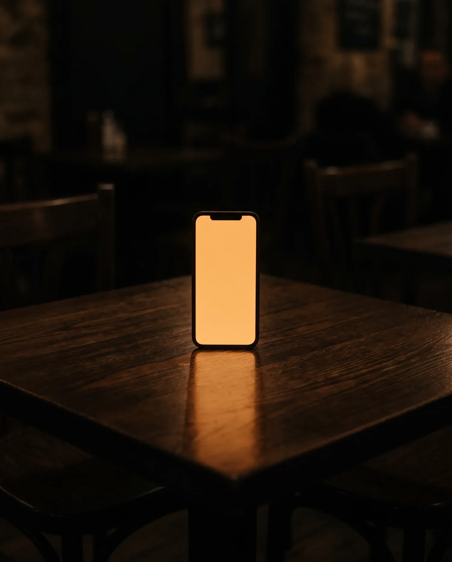 Telefon pe o masă de lemn, cu ecranul luminând cald